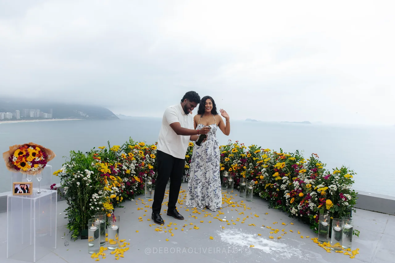 Pareja recién comprometida en el arco de flores en rooftop en Río de Janeiro
