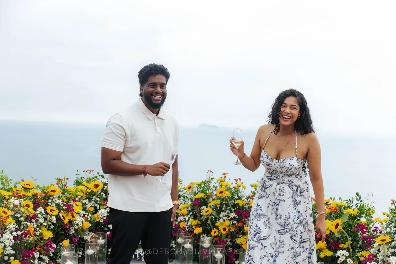 Devshanth y Thanujaah brindando con el mar detrás en Río