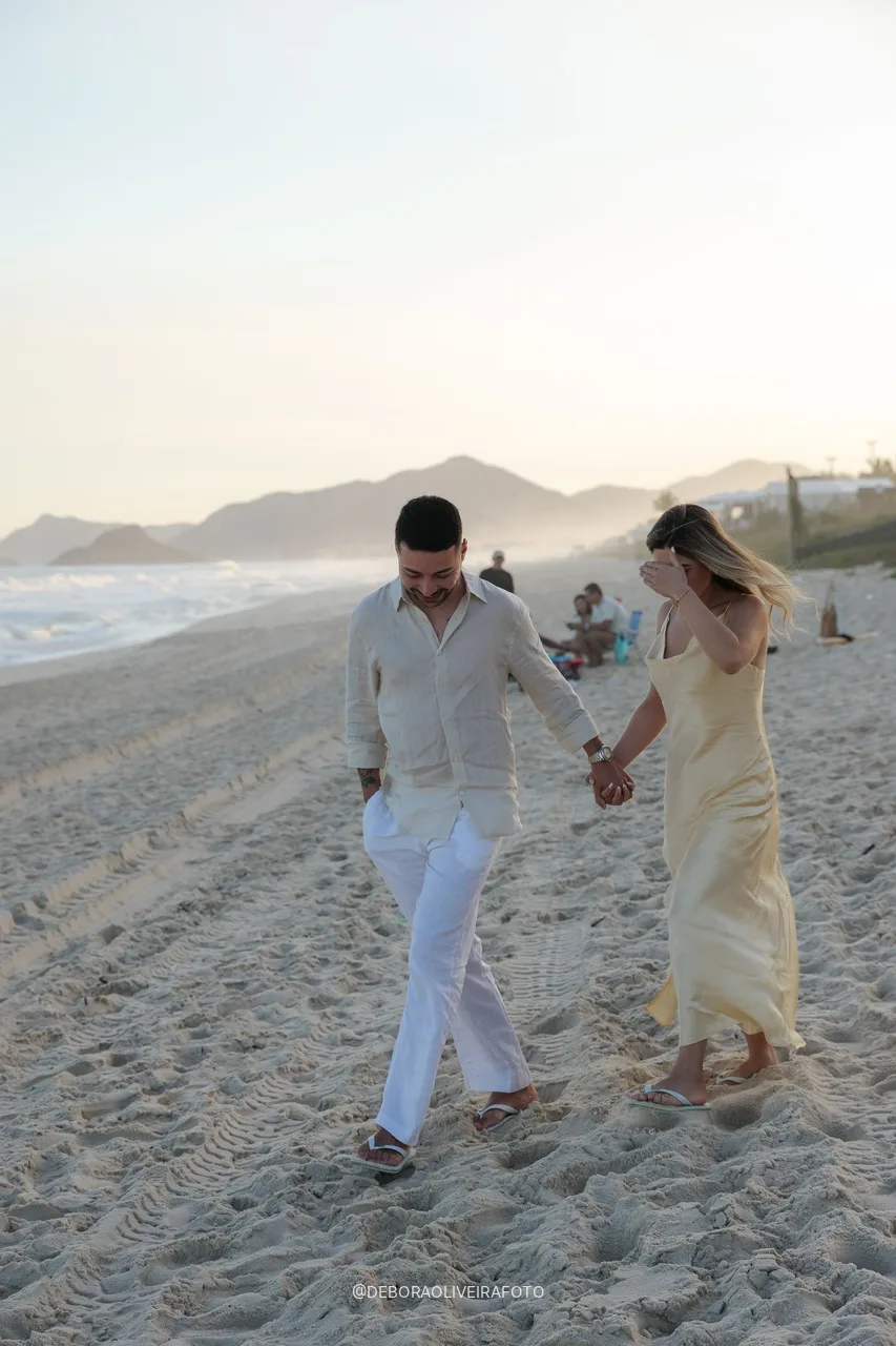 Eduardo e Isabely caminhando de mãos dadas na praia antes do pedido