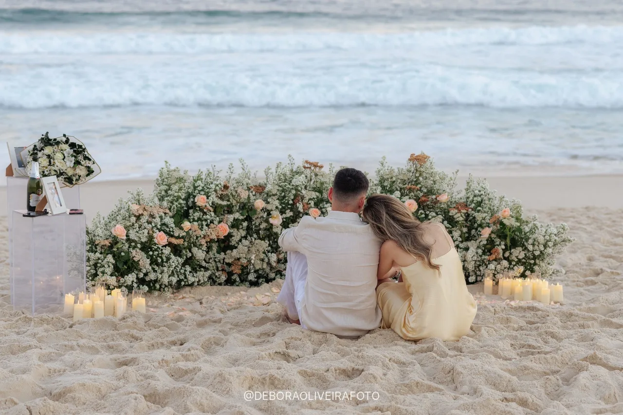 Casal sentado junto ao jardim de flores e às velas de frente para o mar