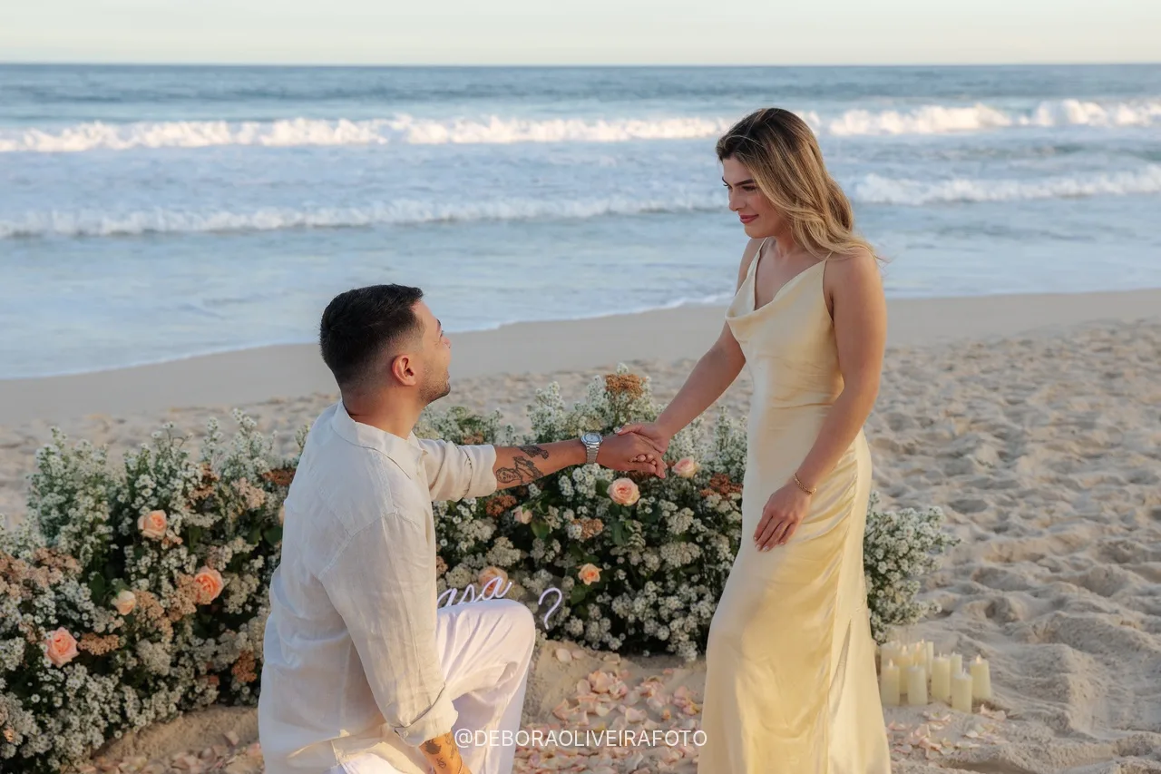 Eduardo de joelho pedindo Isabely em casamento em frente ao jardim de flores