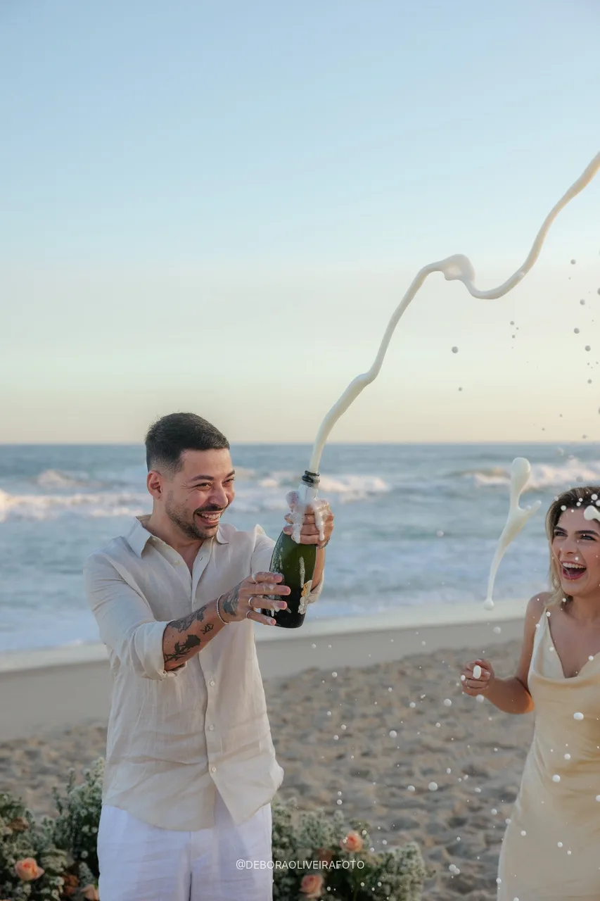 Eduardo estourando o espumante na praia