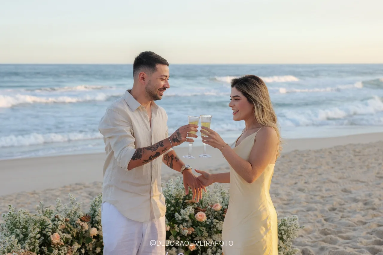 Casal brindando com espumante depois do pedido na praia