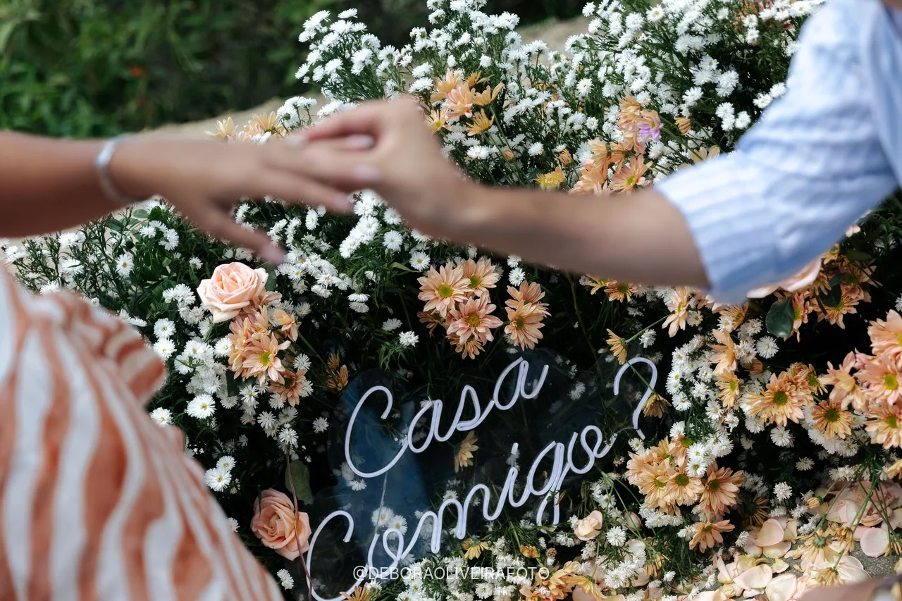 Pareja tomada de la mano sobre el letrero Casa Comigo