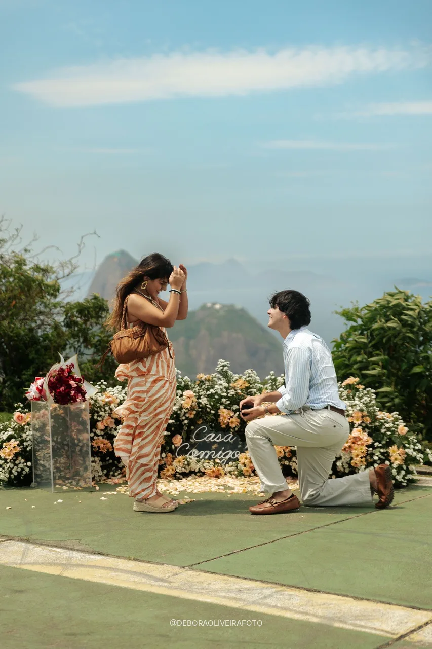 Genaro de rodillas y Alisha emocionada frente a las flores