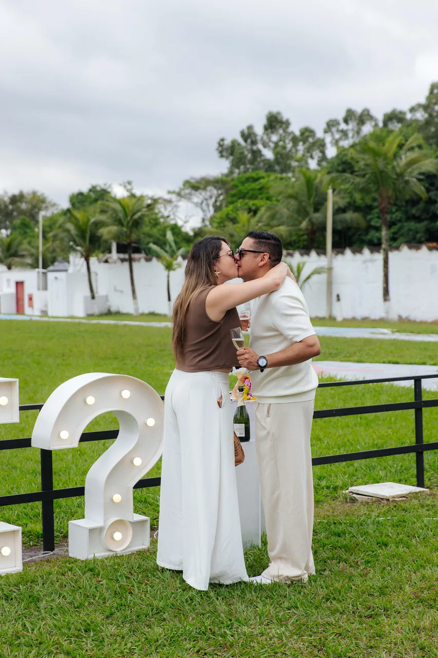 Kiss next to the lit question mark of the Marry Me sign
