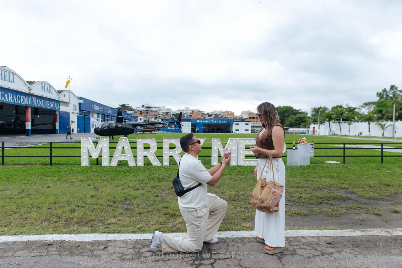 Juan proposing on one knee to Andrea at a heliport in Rio de Janeiro