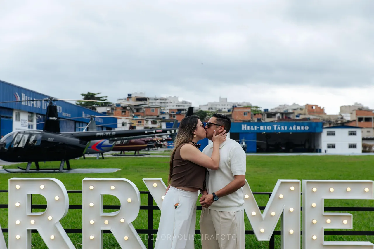 Kiss behind the Marry Me sign with helicopters in the background in Rio de Janeiro