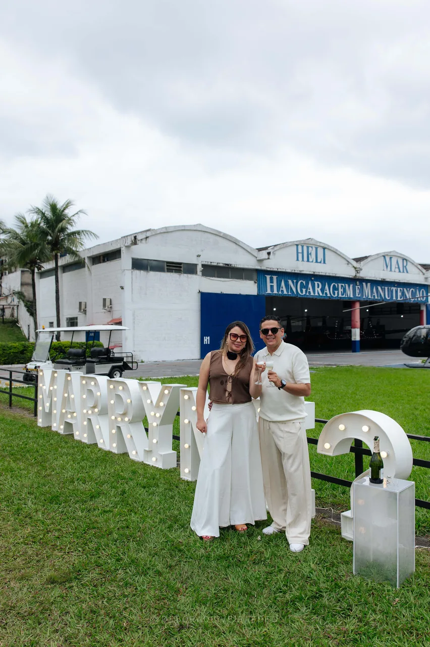 Juan and Andrea standing by the Marry Me sign in front of the hangar