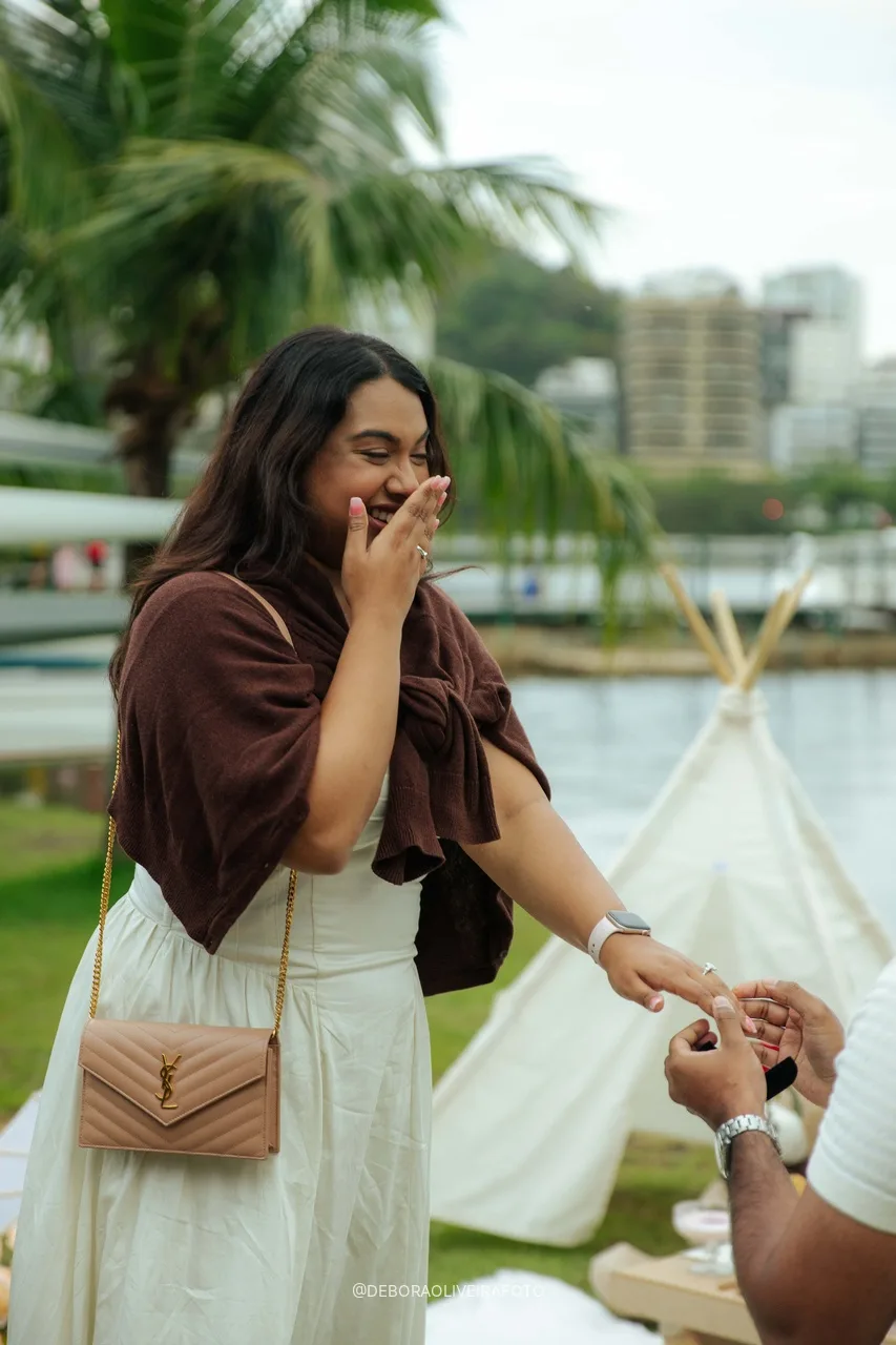 Anisha com a mão na boca enquanto Naveen mostra o anel