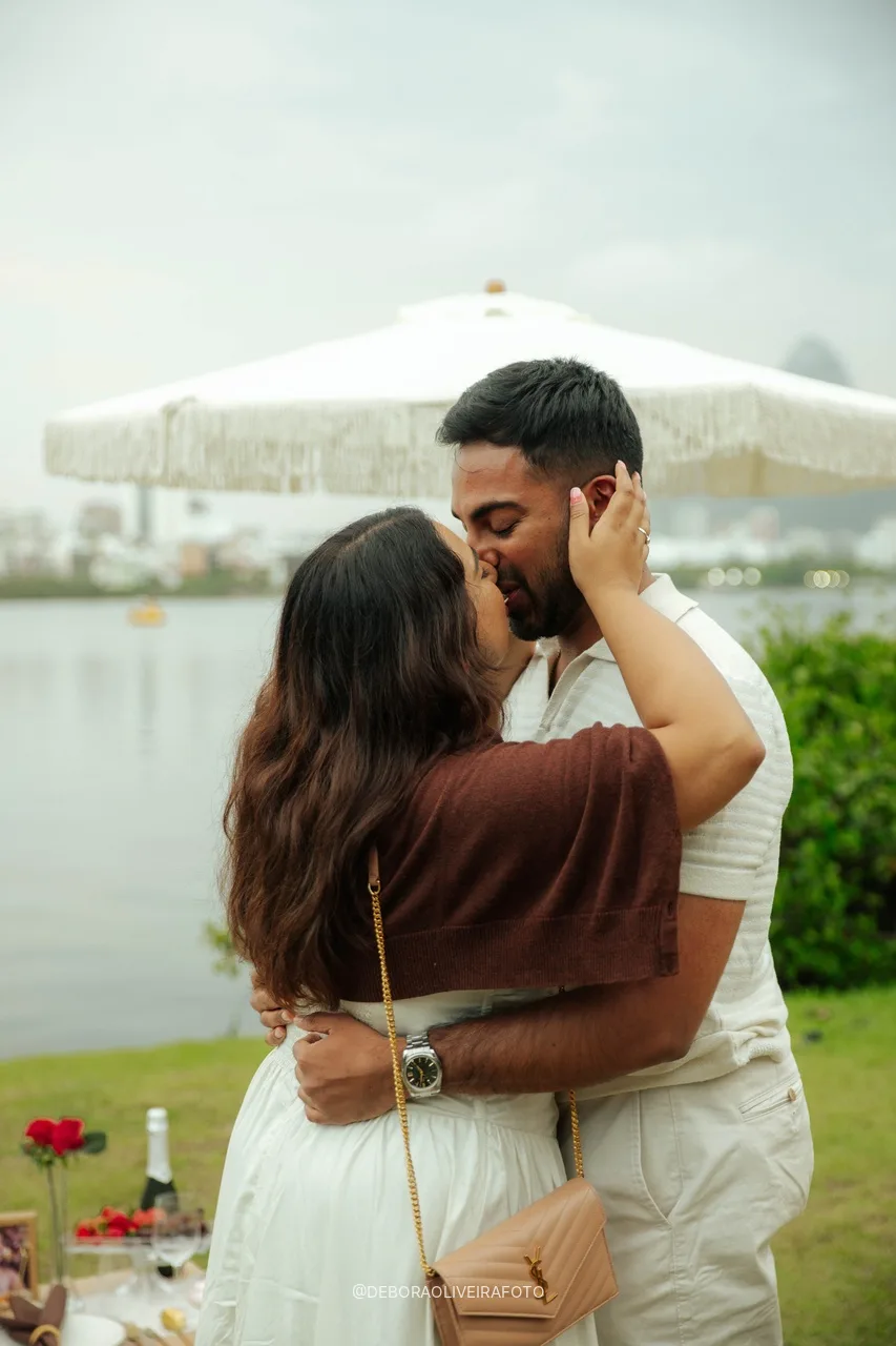 Naveen e Anisha se beijando sob o guarda-sol do piquenique