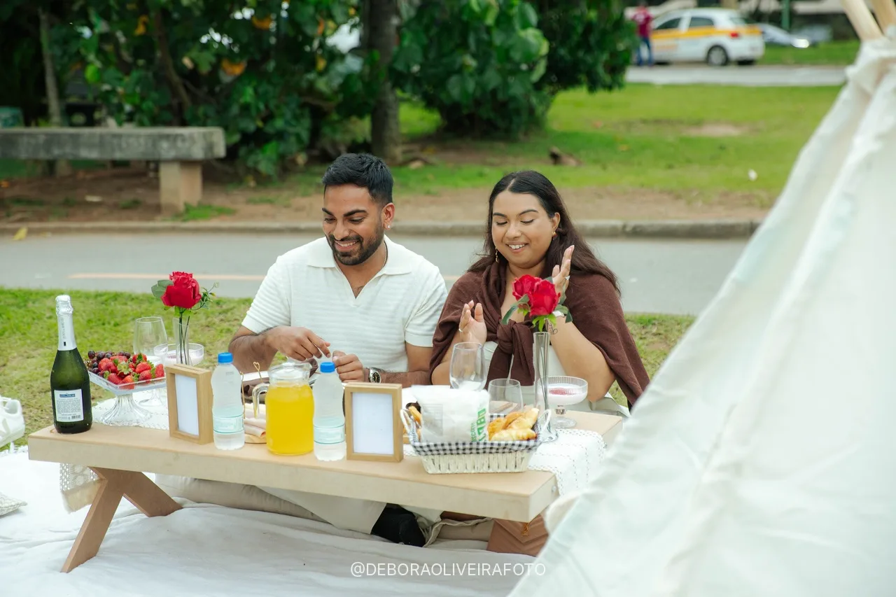Casal noivo sentado na mesa do piquenique com flores