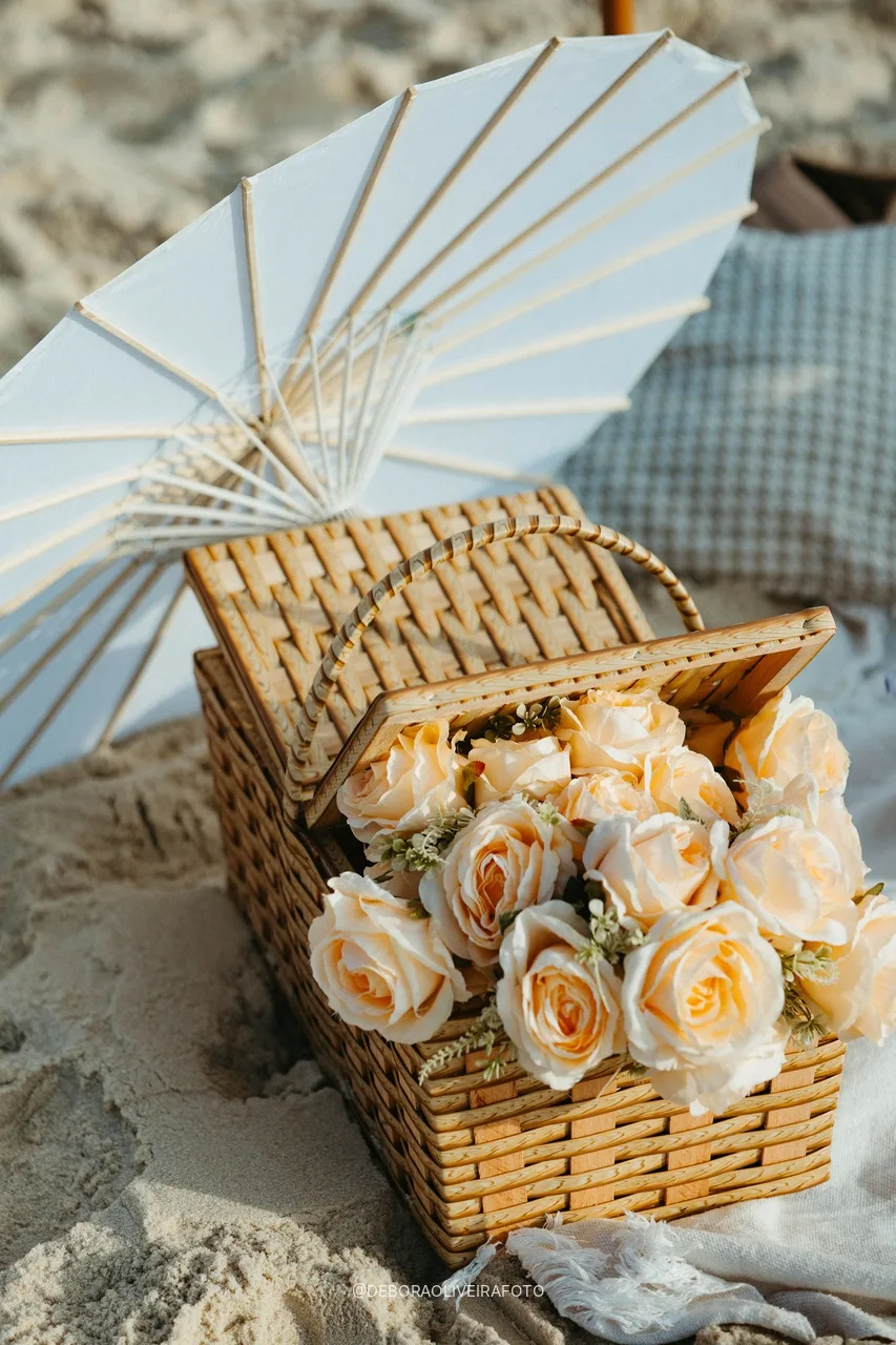 Basket of roses and parasol at the beach picnic