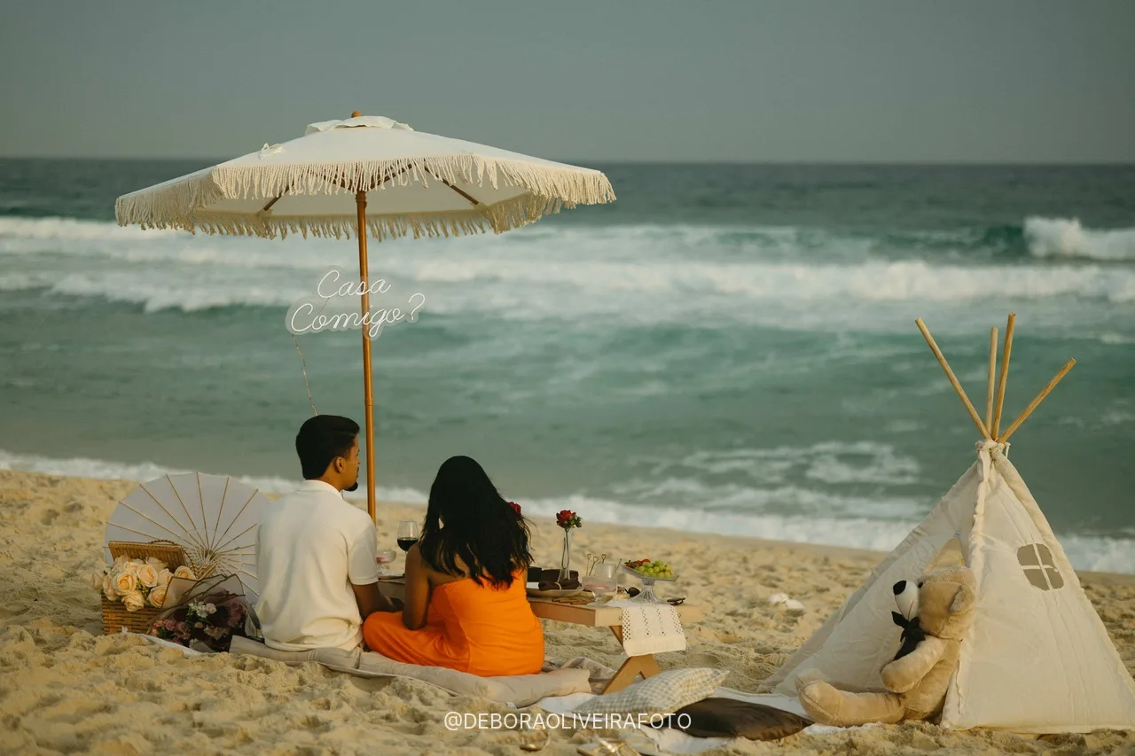Couple sitting at the picnic under the umbrella facing the sea