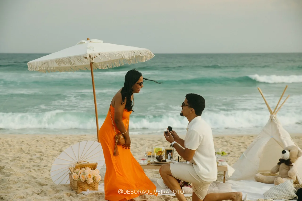 Beach picnic marriage proposal in Rio de Janeiro: Samuel on one knee in front of Emile