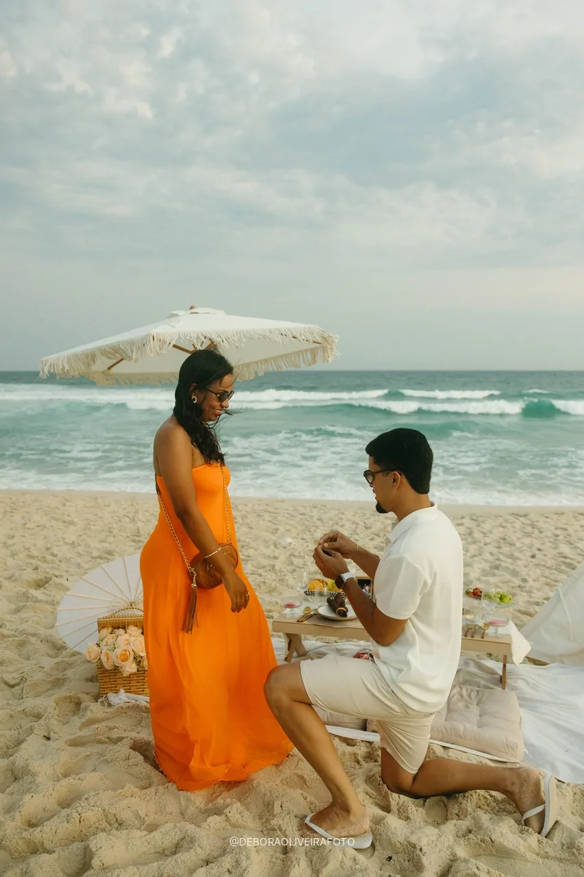 Samuel proposing on one knee under the fringed umbrella