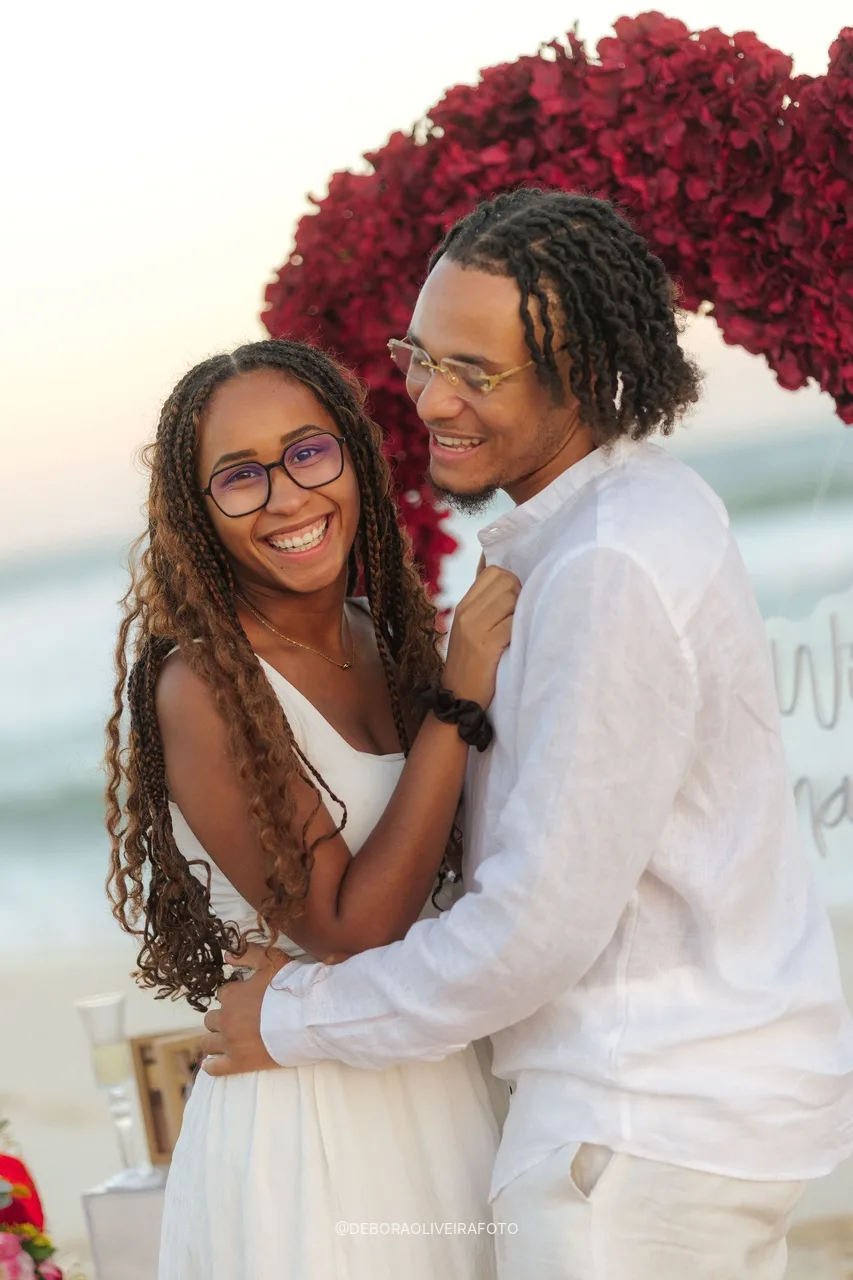 Pareja recién comprometida abrazada y sonriendo junto a las rosas