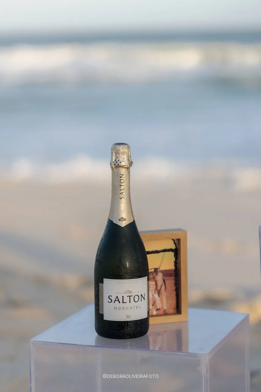 Espumante y foto de la pareja en el soporte de acrílico junto al mar