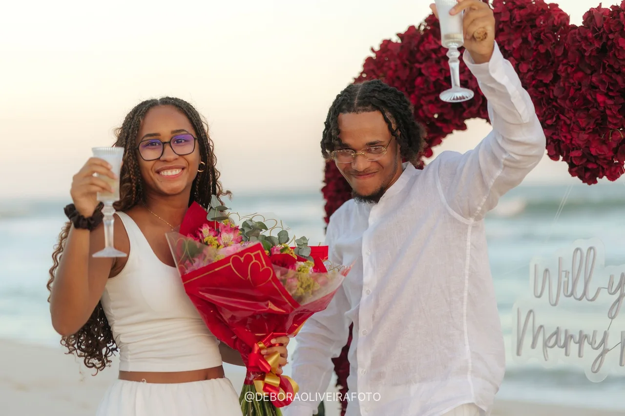 Pareja brindando después del pedido de casamiento en la playa